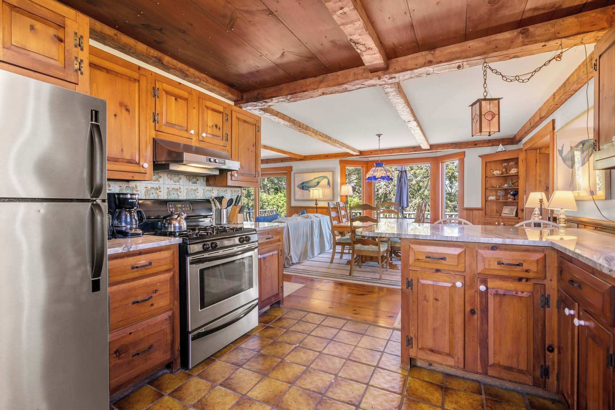 A spacious kitchen with wooden cabinets, a stainless steel refrigerator, a stove, and a dining area with a table and chairs.