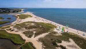 An aerial view of a beach with a sandy shore, a small inlet, and a clear blue sky. - Stunning Water Views 2 Decks! By Beach! (Chatham)