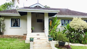 A house with a covered porch, a stone pathway leading to the entrance, and a variety of plants in the garden. - Mock Turtle is an Enchanting & Affordable Retreat! (Black Rock)