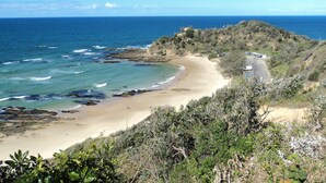 Une route côtière bordée d’une plage et de formations rocheuses.