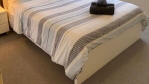 Une chambre d’hôtel moderne dotée d’un grand lit, d’une table de chevet avec une lampe et d’une fenêtre donnant sur l’extérieur.