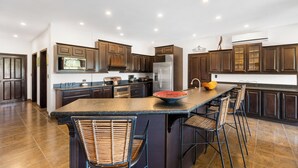 A modern kitchen with dark wood cabinets, stainless steel appliances, and a central island with bar stools.
