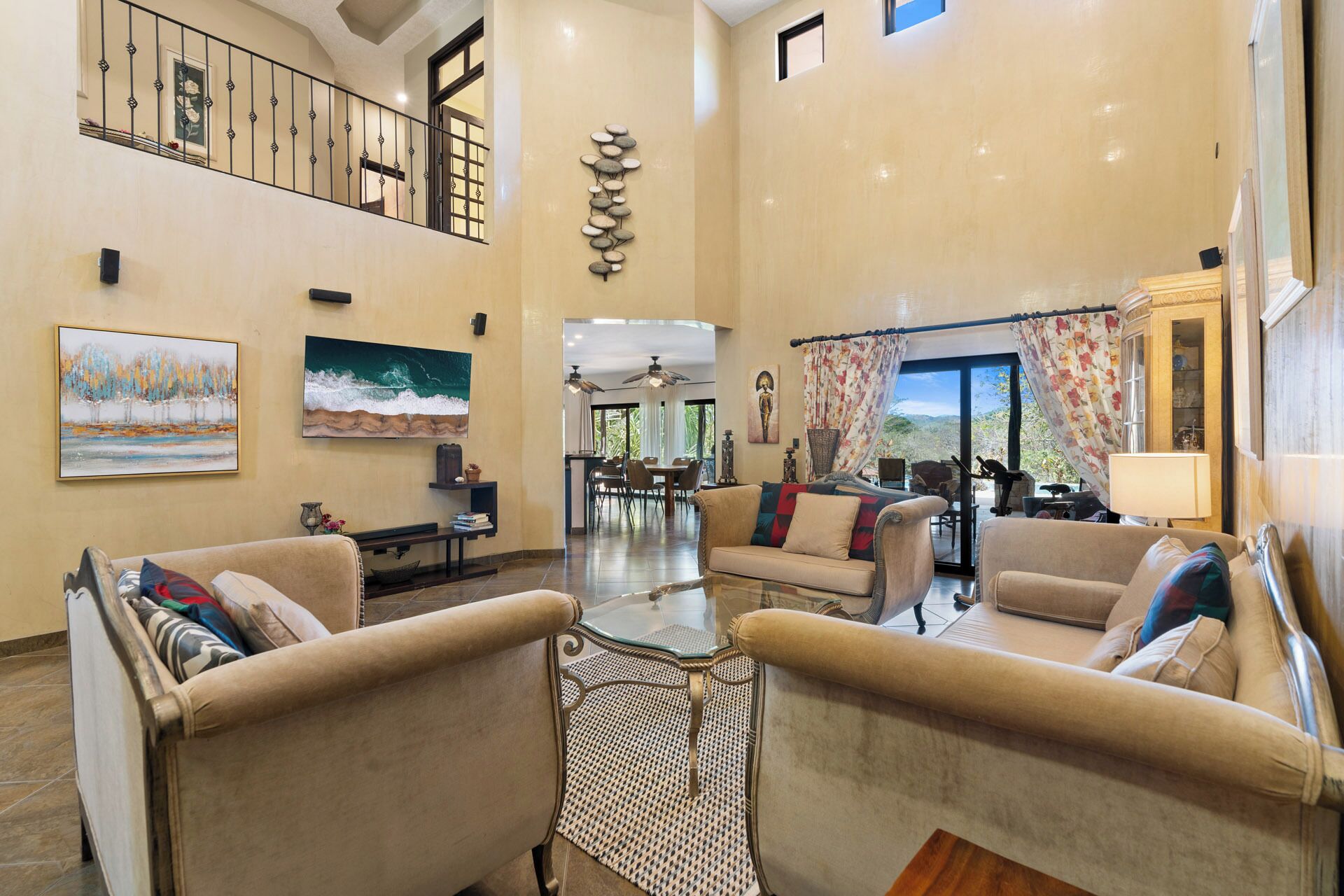 A spacious living area with a high ceiling, a dining area, and a view of the outdoors.