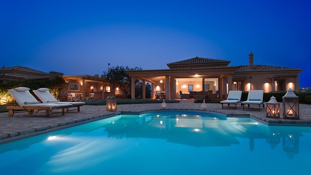Un espace aménagé au bord de la piscine, avec des chaises longues et une terrasse bien éclairée.