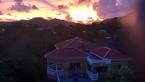 A house with a red roof and a balcony, surrounded by greenery. - YOUR HOME AWAY FROM HOME (Vieux Fort)