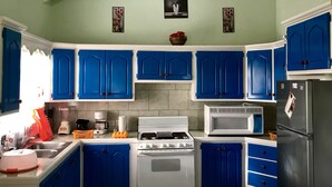 A kitchen with blue cabinets, a stove, a microwave, and a refrigerator. - YOUR HOME AWAY FROM HOME (Vieux Fort)