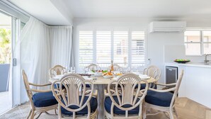 Ein Essbereich mit einem für sechs Personen gedeckten Tisch, umgeben von Korbstühlen mit blauen Kissen.