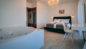A modern bedroom with a large bathtub, a bed with a dark headboard, and a dining table with chairs. - Apartment **** "Lumin 4" 52 m2 (Senj)