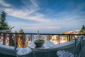 Ein Balkon mit Tisch und Stühlen, einer Obstschale und Blick auf eine entfernte Skyline.