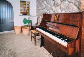 Grand piano sits in a spacious room with an arched doorway, accompanied by a bench and planters.