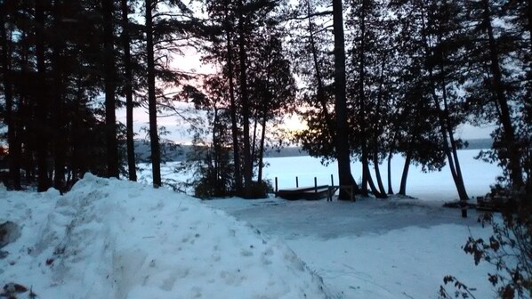 A snowy landscape with a body of water and trees in the background.