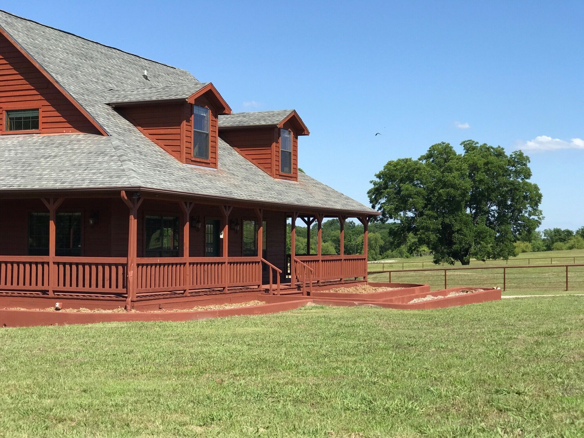 A large, red wooden house with a porch and multiple windows.