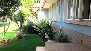 A residential house with a well-maintained garden, a stone sculpture, and a tiled entrance.