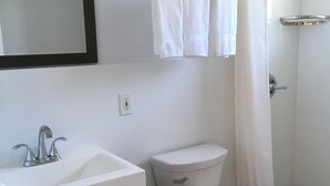 Een badkamer met toilet, wastafel en douche.