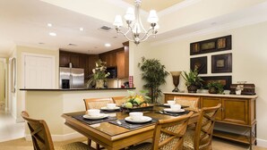 A dining area with a wooden table, chairs, and a chandelier. - Modern Coziness: Orlando Apartment (Kissimmee)