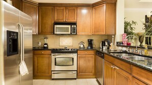 A kitchen with wooden cabinets, stainless steel appliances, a microwave, a stove, and a sink. - Modern Coziness: Orlando Apartment (Kissimmee)