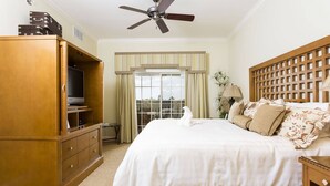 A hotel room with a bed, a wooden wardrobe, a ceiling fan, and a window with curtains. - Modern Coziness: Orlando Apartment (Kissimmee)