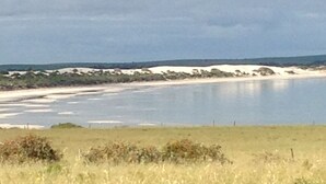 Eine Küstenlandschaft mit Sandstrand und ruhigem Gewässer.