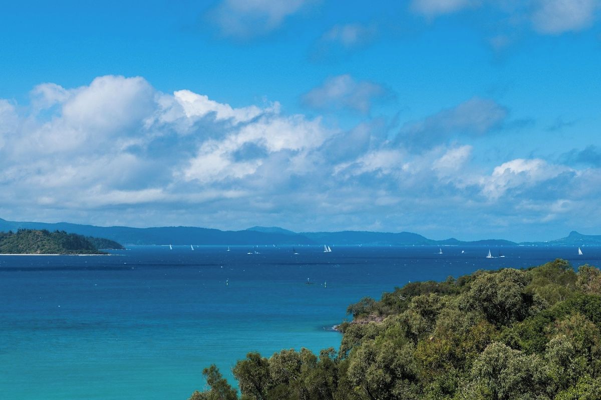 Un paysage côtier avec un ciel dégagé, une mer calme et des montagnes à l’horizon.