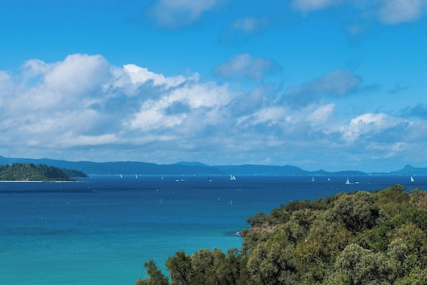 A coastal landscape with a clear sky, calm sea, and distant mountains.