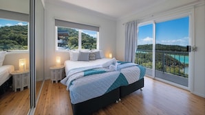 Un dormitorio con cama, mesitas de noche, una ventana y un balcón con vistas.