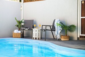 A poolside area with a lounge chair, a small table with drinks, and potted plants. - Picturesque on Passage (Shute Harbour)