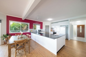 A modern kitchen with a central island, wooden dining table, and chairs. - Picturesque on Passage (Shute Harbour)