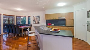 Uma cozinha moderna com uma ilha central, armários de madeira e uma área de jantar com mesa e cadeiras.