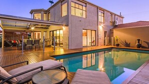 Uma casa moderna com piscina, área de estar externa e um pátio coberto.