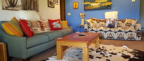 Un soggiorno con un divano blu, un tavolino in legno e un tappeto in pelle di vacca.