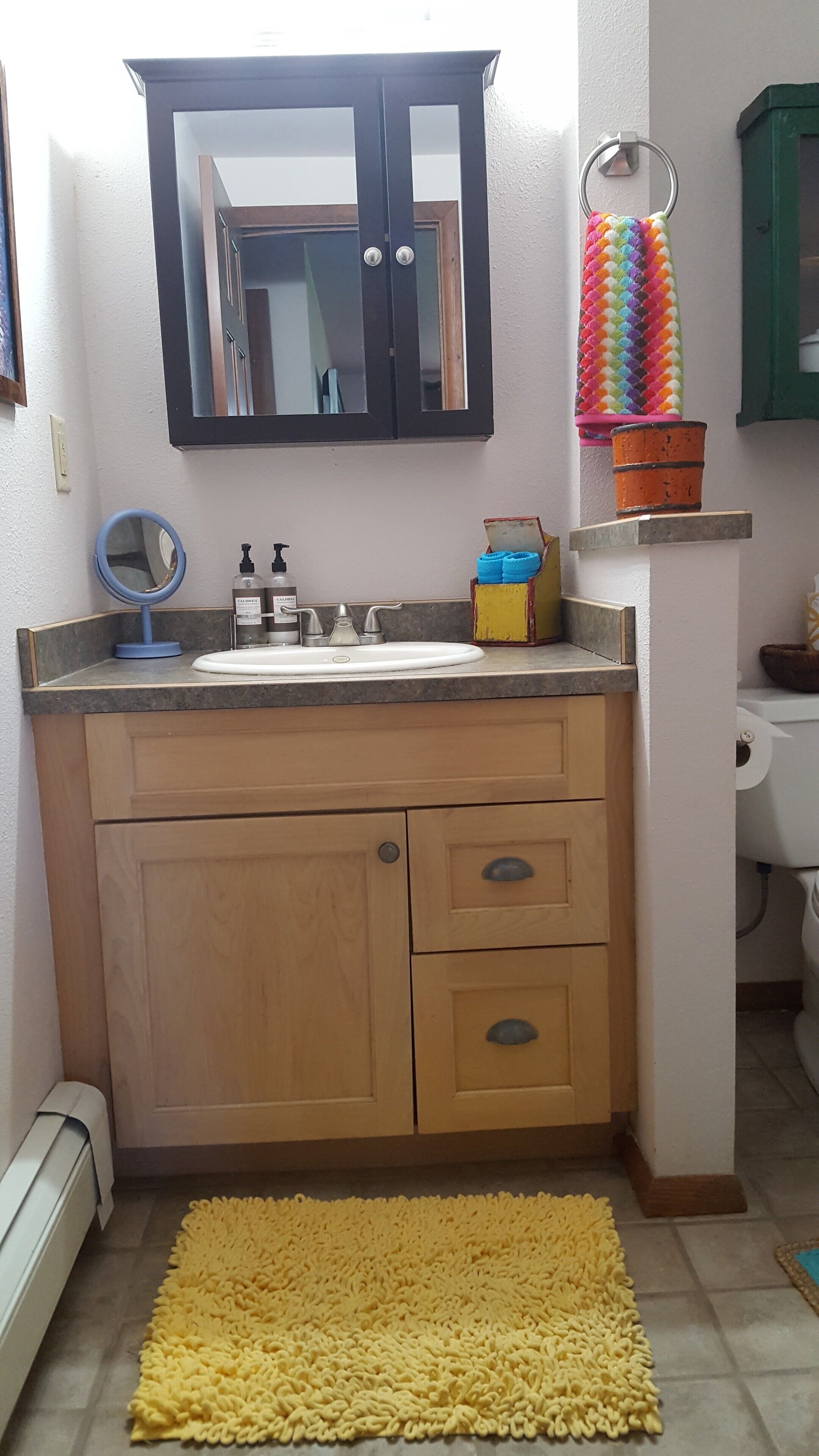 A bathroom with a sink, mirror, and cabinet.