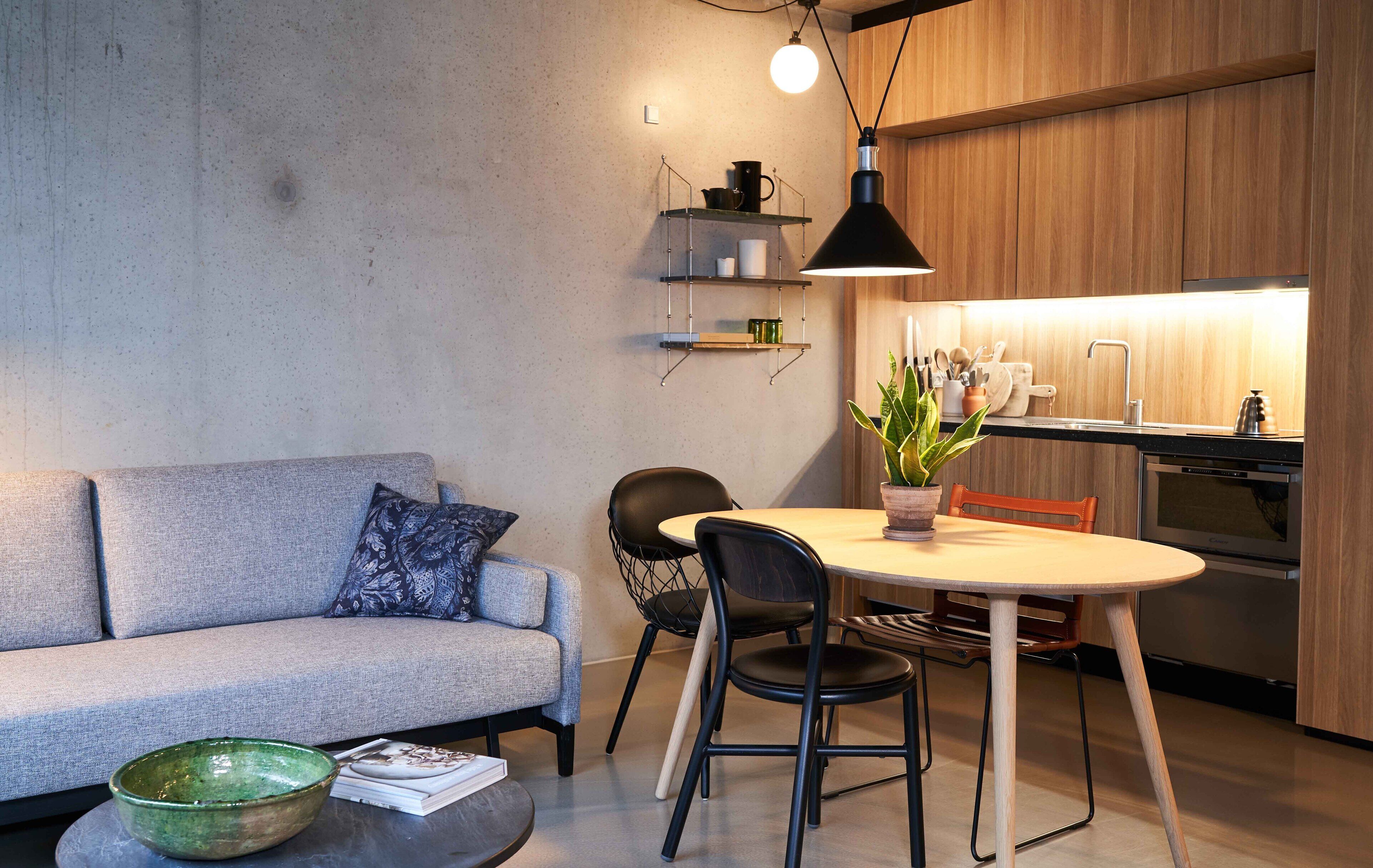 A modern kitchen with wooden cabinets, a built-in oven, and a dining area with a round table and chairs.