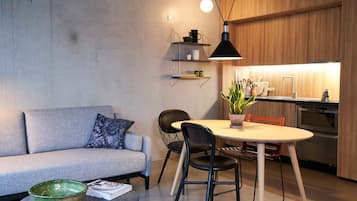 Una cocina moderna con armarios de madera, horno empotrado y comedor con una mesa redonda y sillas.