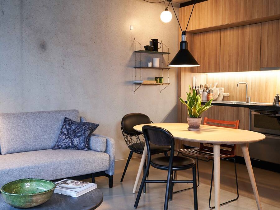 A modern kitchen with wooden cabinets, a built-in oven, and a dining area with a round table and chairs.