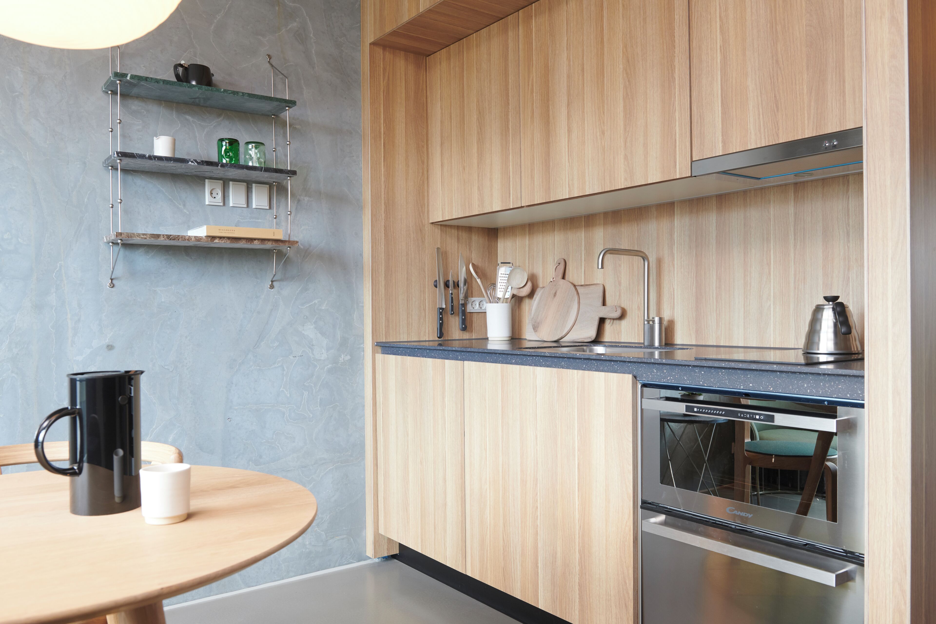 Una cocina moderna con armarios de madera, horno empotrado y encimera con utensilios de cocina.