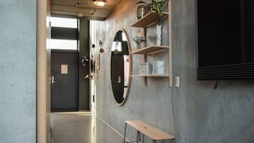Een hal met een houten bank, een grote spiegel en planken met planten en boeken.