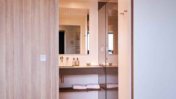 A modern bathroom with a wooden vanity, a glass shower enclosure, and a large mirror.