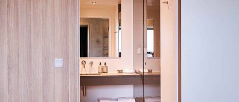 A modern bathroom with a wooden vanity, a glass shower enclosure, and a large mirror.