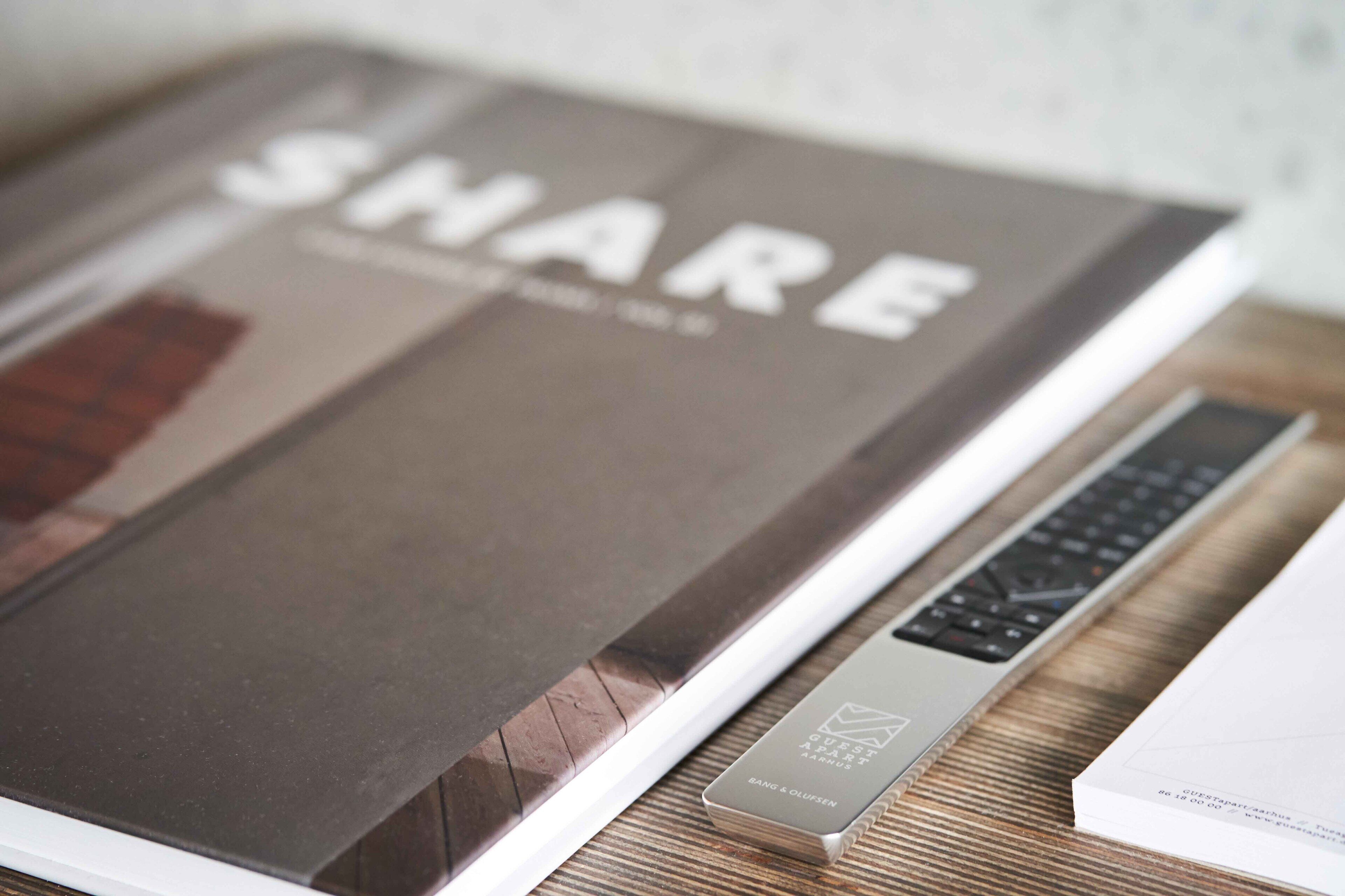 A book titled "SHARE" on a wooden table next to a laptop.