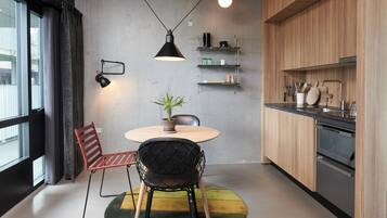 A modern kitchen with a round table, two chairs, a potted plant, and built-in appliances.