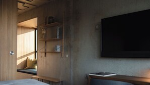 A compact hotel room with a bed, a desk, and a TV mounted on the wall. - Hotel GUESTapart (Aarhus)