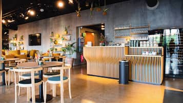 A modern cafe interior with wooden furniture, a bar area, and various plants.