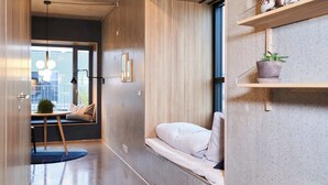 A modern interior with a built-in bench, a potted plant, and a view through a large window. - Hotel GUESTapart (Aarhus)