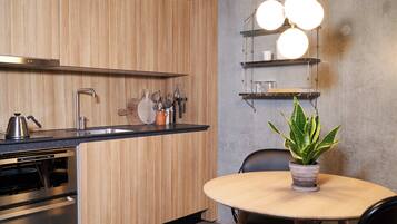 A modern kitchen with wooden cabinets, stainless steel appliances, and a round dining table with a potted plant.