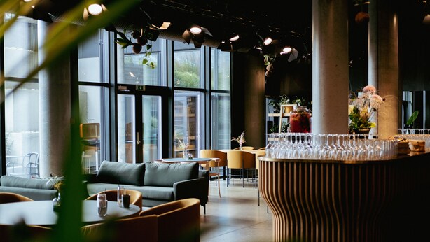 A modern interior with a sofa, chairs, a bar area, and large windows. - Hotel GUESTapart (Aarhus)