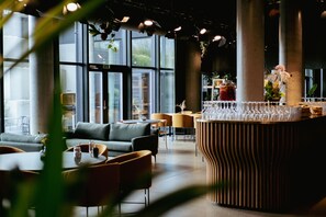 Un intérieur moderne avec un canapé, des fauteuils, un coin bar et de grandes fenêtres.