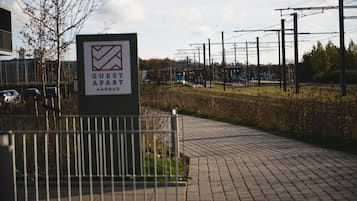 Skilt til et gæsteværelse med et ternet logo, en belagt sti og et hegn.