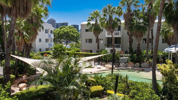 Ein Resort mit Pool, Palmen und modernen Gebäuden im Hintergrund.