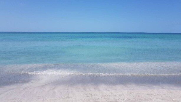 Una playa con agua turquesa cristalina y una orilla arenosa.