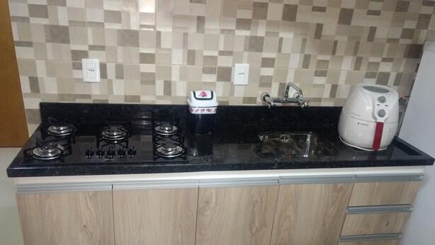A kitchen with a black countertop, four burners, a sink, and a coffee maker. - CORREA PEREIRA RESIDENTIAL APARTMENT 3, sleeps up to 11 people, 3 bedrooms (CANELA)